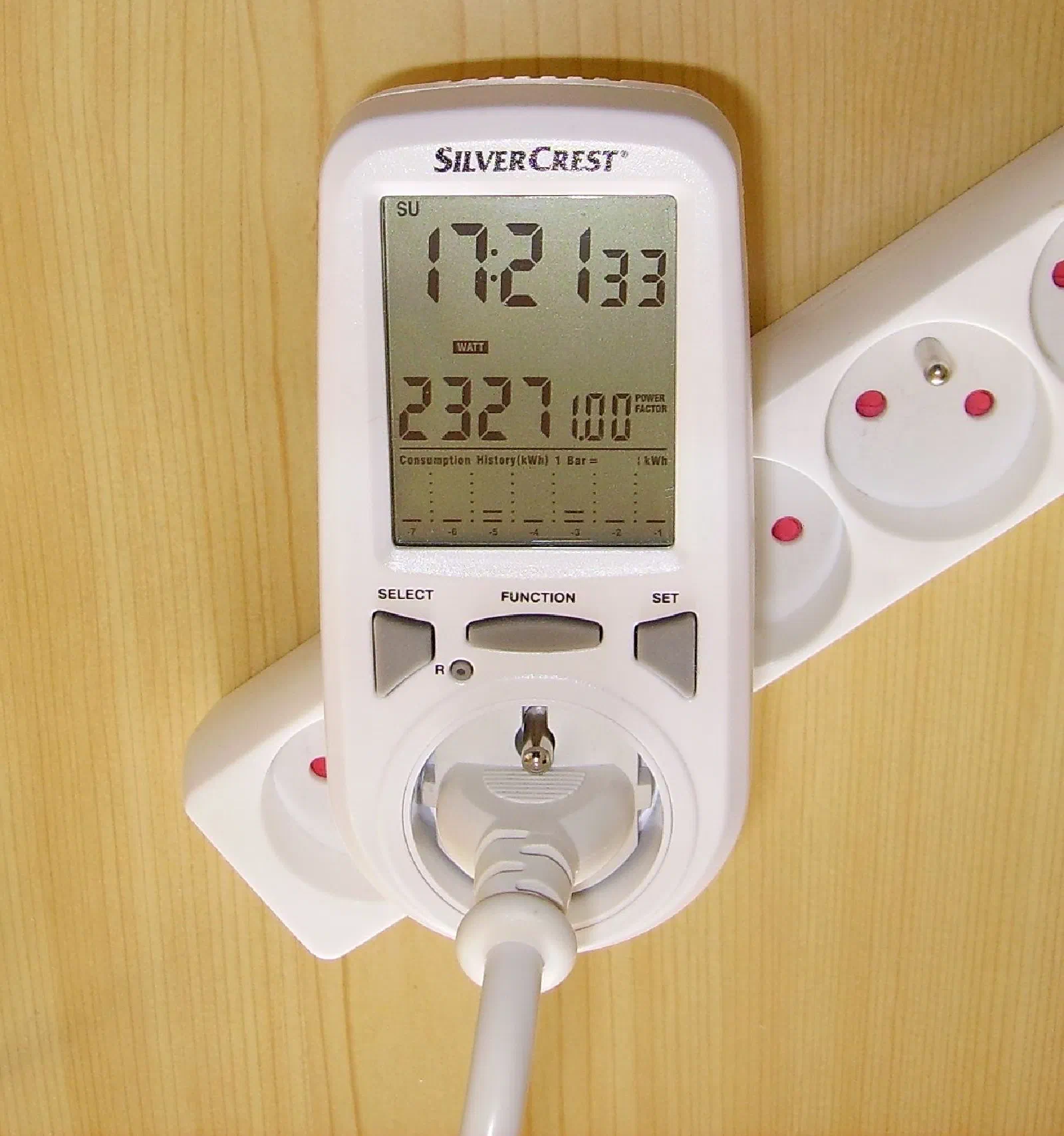 Medidor de energia de tomada ligado na parede, com visor digital mostrando o consumo